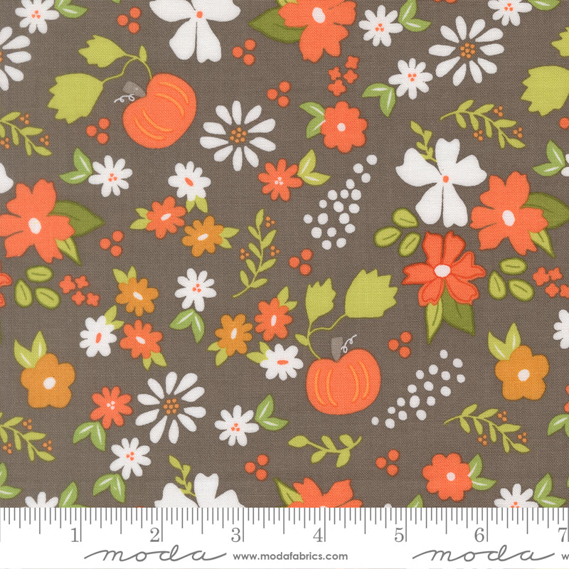 Floral and pumpkin pattern fabric with a ruler for scale on a slate background