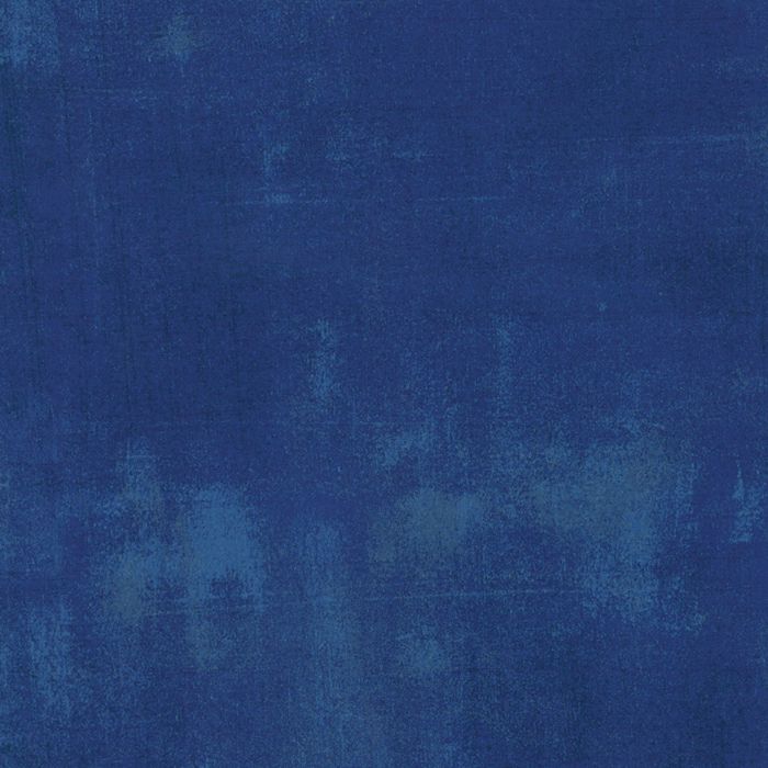 A close-up of a textured blue fabric or material swatch with subtle tonal variation.
