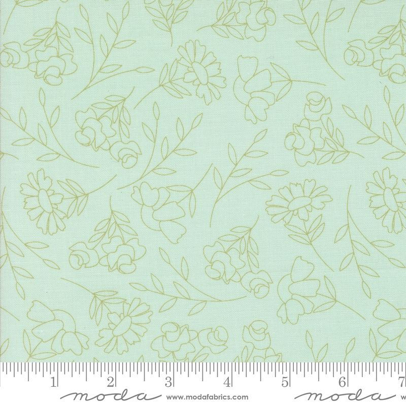 A close-up of a fabric pattern featuring light sage green floral and leaf line drawings on a pale blue background, with a measuring ruler along the bottom edge showing the scale.