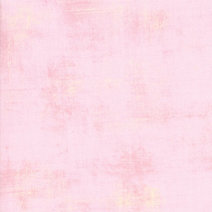 A close-up of a light pink textured fabric with subtle tonal variation and a slightly distressed, brushed finish.