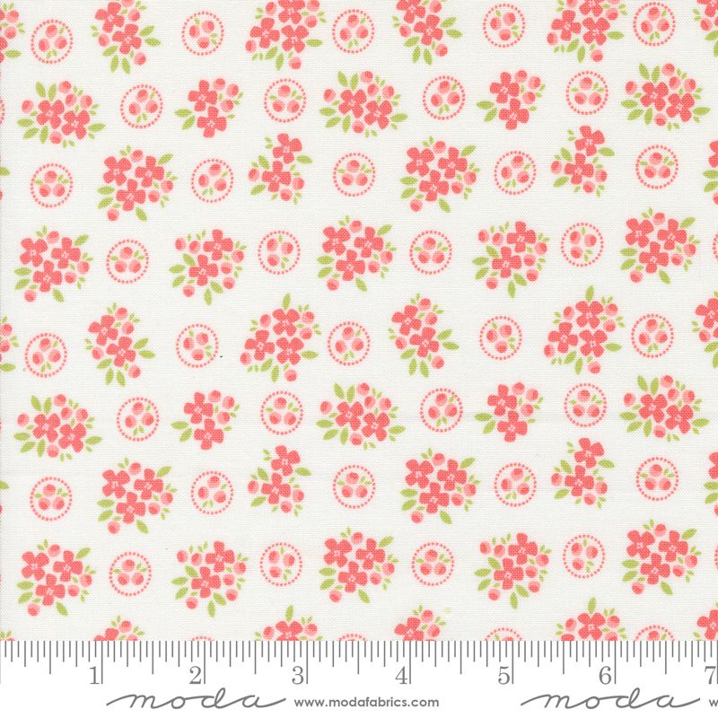 A close-up of a fabric pattern featuring pink floral clusters and green leaves on a white background, with a ruler along the bottom edge showing scale. The brand name 'moda' is visible at the bottom.