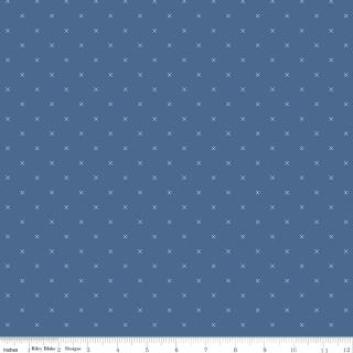 A close-up of a blue fabric with a repeating small white cross pattern, with a ruler along the bottom edge showing scale.
