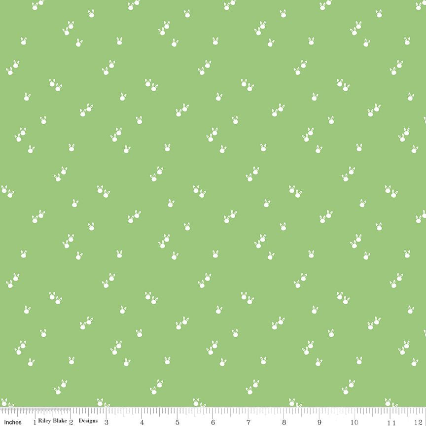 A fabric pattern swatch featuring a light green background with a repeating pattern of small white bunny silhouettes, with a measuring ruler visible along the bottom edge.