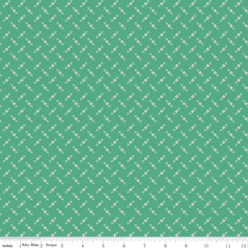 A repeating fabric pattern of small white flowers and leaves on a mint green background, shown with a ruler along the bottom edge to indicate scale.