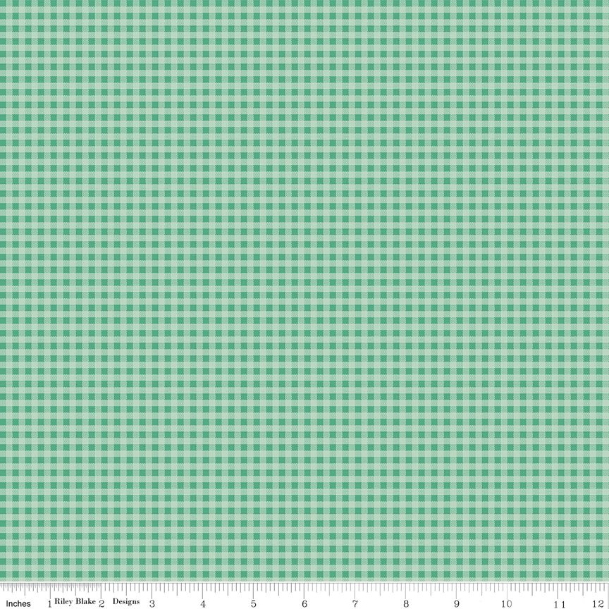 A close-up of a green and white gingham fabric pattern with a ruler along the bottom edge showing inches and the brands R.B.