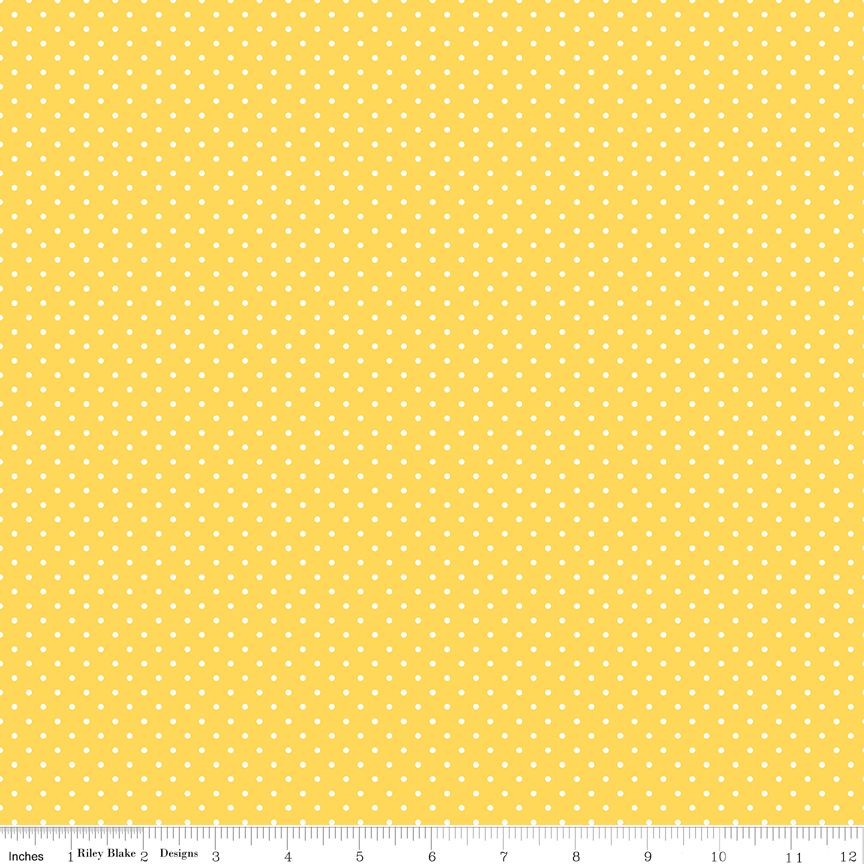 Bright yellow abric with small white polka dots and a ruler at the bottom for scale.