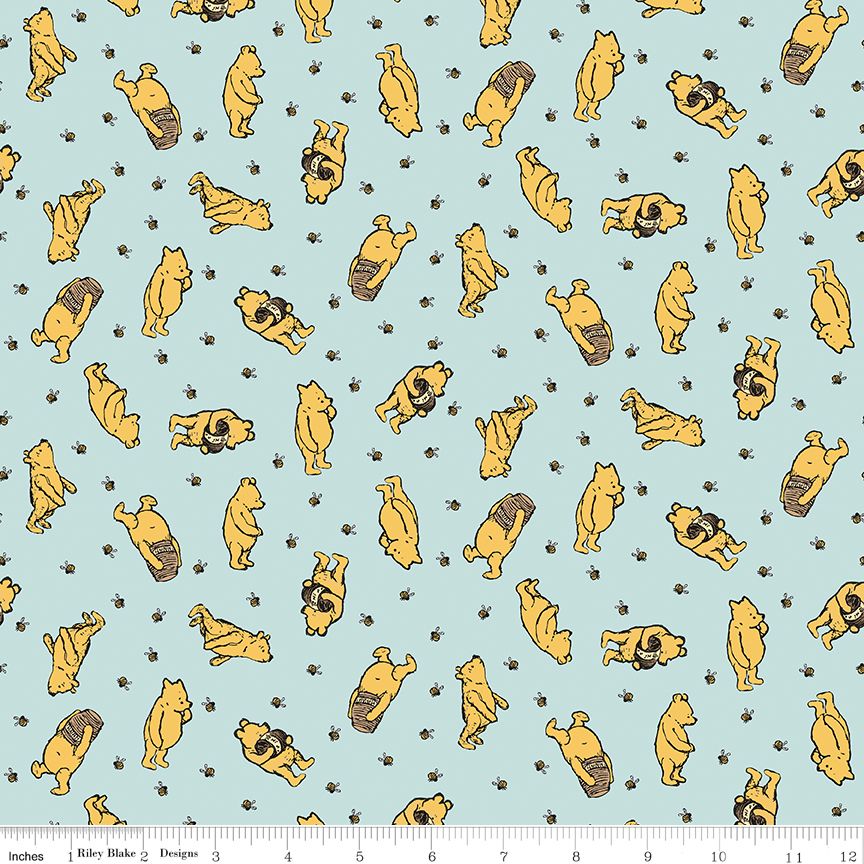 A repeating fabric pattern featuring Winnie the Pooh characters in yellow with bees on on a light blue background, with a small ruler at the bottom showing measurements.