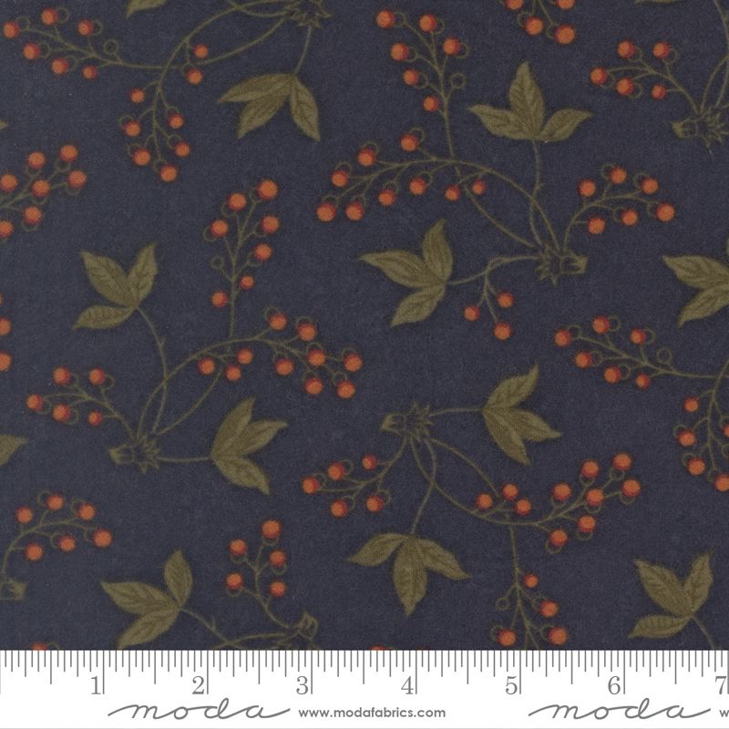 A close-up of a fabric pattern featuring olive green leaves and vines with small orange berries on a dark navy blue background, with a white ruler at the bottom showing measurements.
