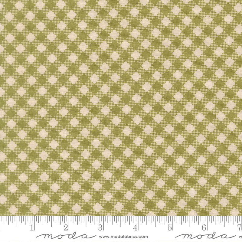 A close-up of a fabric pattern with an olive green and cream gingham-style check design, shown with a ruler along the bottom edge for scale. The brand name 'moda' and website 'www.