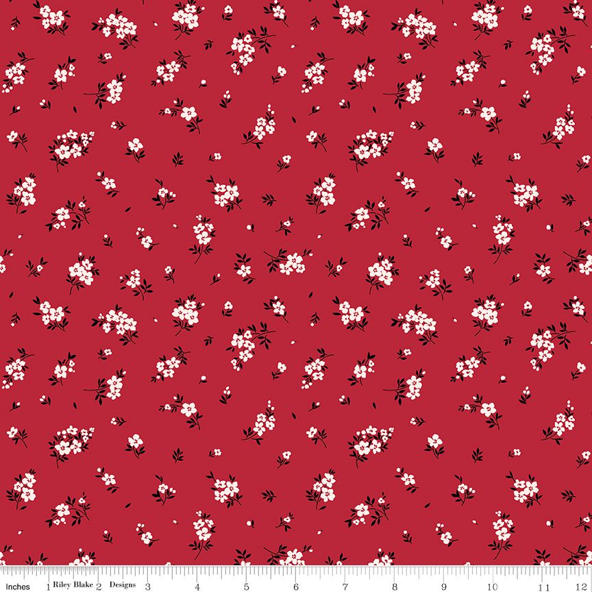 Red fabric with a repeating white and black cherry blossom floral pattern, shown flat with a ruler at the bottom indicating scale.