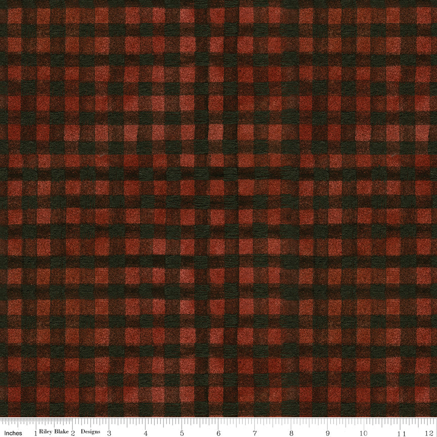 A close-up of a red and black gingham plaid fabric pattern with a white ruler visible along the bottom edge.