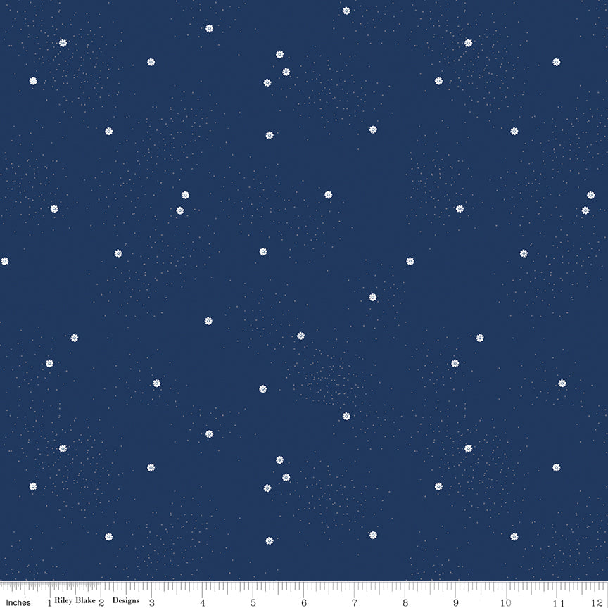 A close-up of a fabric pattern featuring small, scattered white daisies and dots on a navy background, with a ruler visible along the bottom edge for scale.
