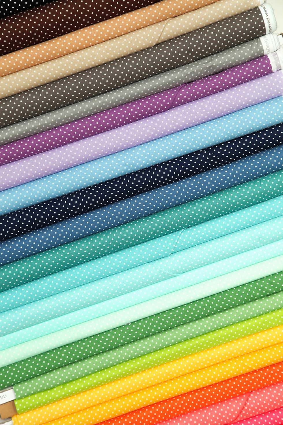 Stacked bolts of Swiss Dot fabric by Riley Blake Designs showing a sampling of available colorways