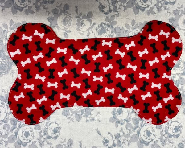 Bone shaped dog bowl placemat with a red background and black and white dog bones.