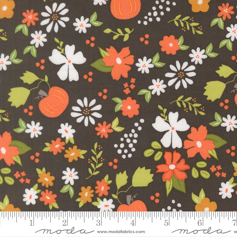 Fabric with cheerful pumpkins and flowers on a charcoal background.