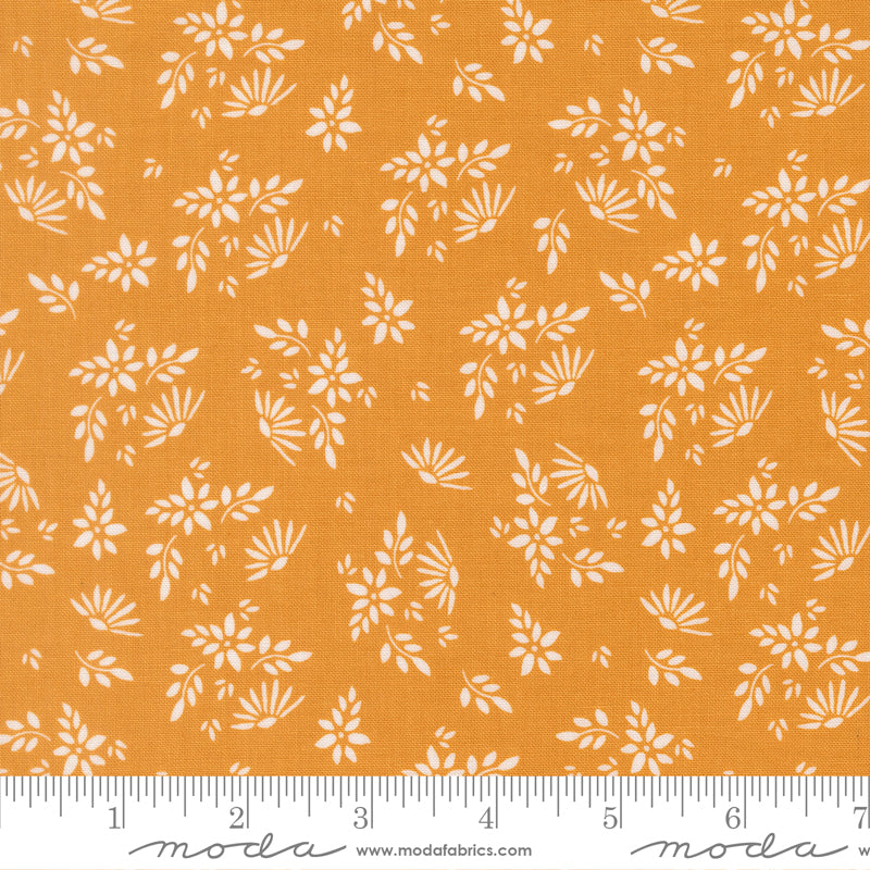 Fabric with a warm golden background print featuring white scattered flowers and leaves.