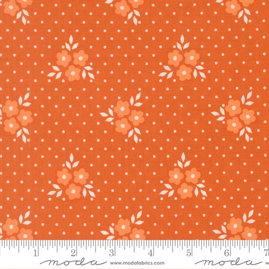 Deep orange fabric with pale orange flowers with white centers, white leaves, and white polka dots. 