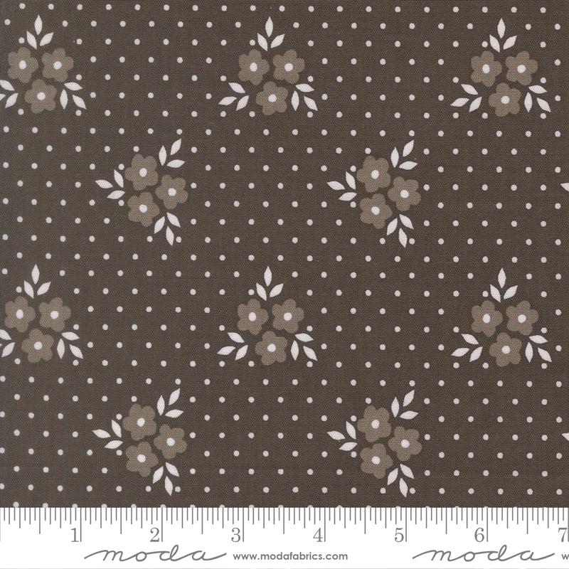 Fabric swatch with a deep charcoal background with light gray flowers and white leaves and polka dots. 