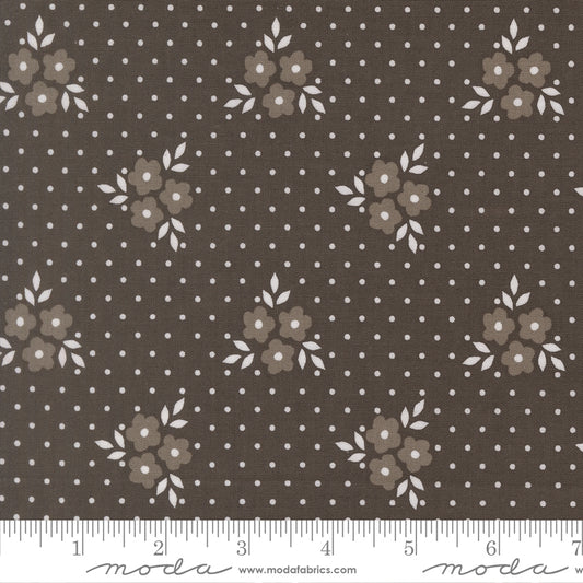 Fabric swatch with a deep charcoal background with light gray flowers and white leaves and polka dots. 