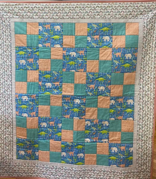 Handmade lap quilt in coordinating cotton fabrics, approximately 42 by 48 inches, laid flat to show pattern detail