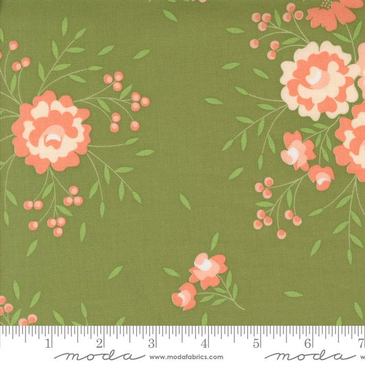 Green fabric with a floral print featuring coral-pink and cream flowers, green leaves, and small pink berry clusters. A white ruler is visible along the bottom edge showing measurement markings, and the brand name 'moda' appears at the bottom.