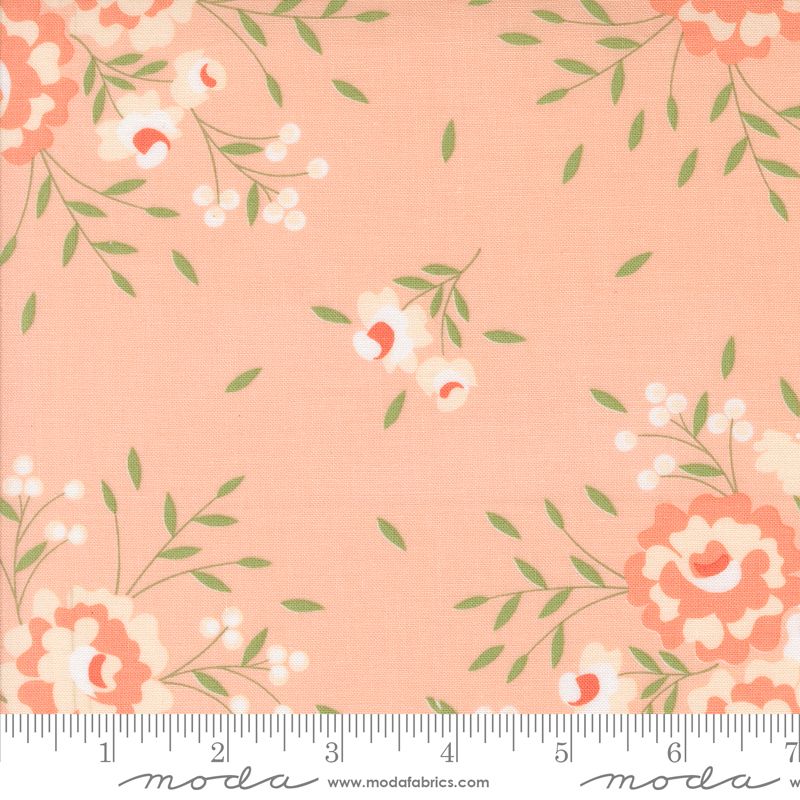 A close-up of a fabric pattern featuring peach and coral flowers with green leaves on a soft peach background, with a ruler at the bottom showing the scale.