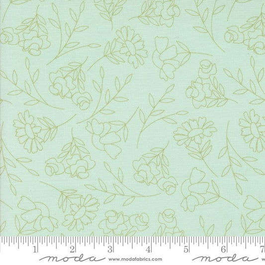 A close-up of a fabric pattern featuring light sage green floral and leaf line drawings on a pale blue background, with a measuring ruler along the bottom edge showing the scale.