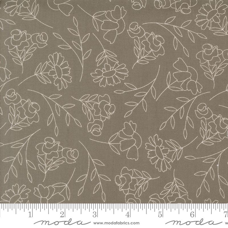 A close-up of a fabric pattern featuring delicate white floral and leaf line drawings on a warm slate gray background, with a ruler along the bottom edge showing the scale.