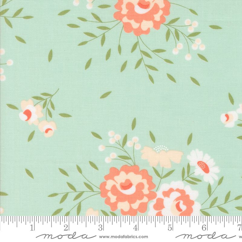 Floral fabric pattern on a pale blue background with coral, peach, white, and cream flowers and green leaves, shown with a ruler at the bottom for scale. The brand Modra is visible on the ruler watermark.