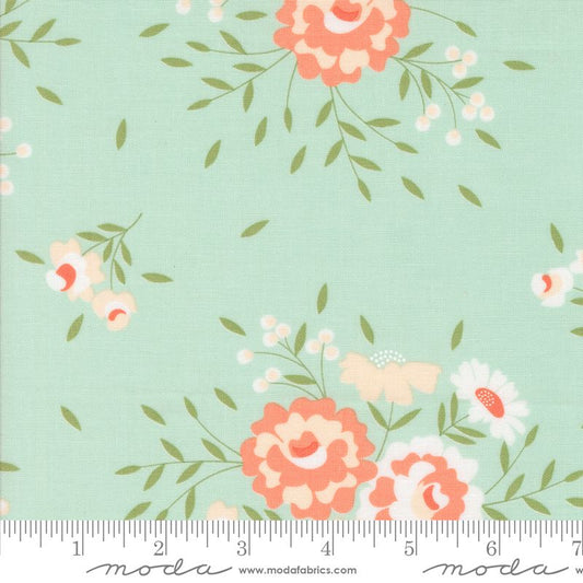 Floral fabric pattern on a pale blue background with coral, peach, white, and cream flowers and green leaves, shown with a ruler at the bottom for scale. The brand Modra is visible on the ruler watermark.
