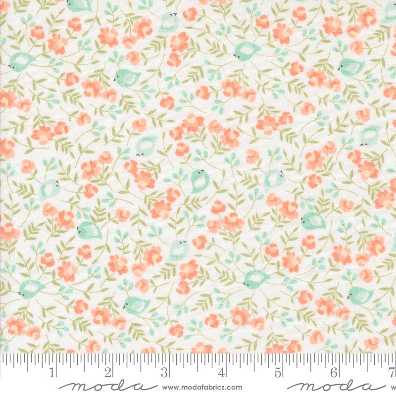 A close-up of a fabric pattern featuring small coral-pink flowers, light green leaves, and pale blue birds on a white background, with a measuring ruler along the bottom edge and Modas Fabrics branding.