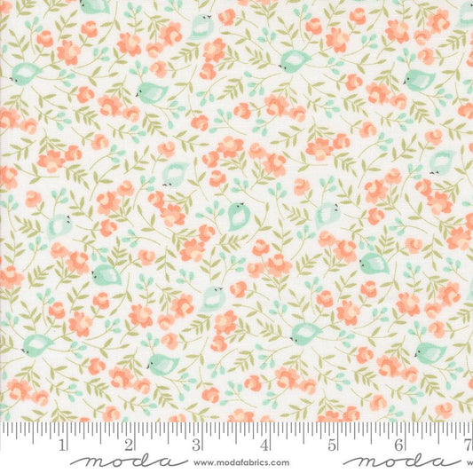 A close-up of a fabric pattern featuring small coral-pink flowers, light green leaves, and pale blue birds on a white background, with a measuring ruler along the bottom edge and Modas Fabrics branding.
