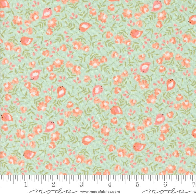 A repeating fabric pattern featuring small pink birds, coral flowers, and green leaves on a pale pale blue background, with a ruler and Modas Fabrics branding along the bottom edge.