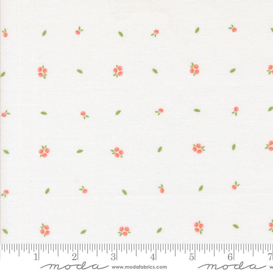 White fabric with a repeating pattern of small pink flowers with green leaves and stems, shown with a measuring ruler along the bottom edge.