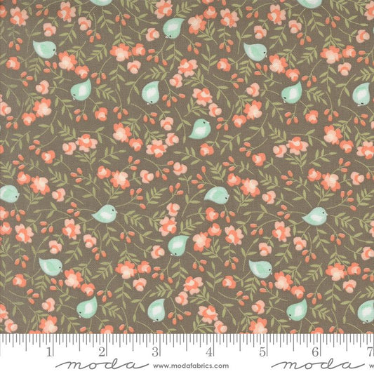 A fabric pattern swatch featuring a slate gray background with a repeating print of small pale blue birds, coral-pink flowers, and green leaves, with a white ruler along the bottom edge showing measurements. The brand name 'modafabrics' is visible at the bottom.