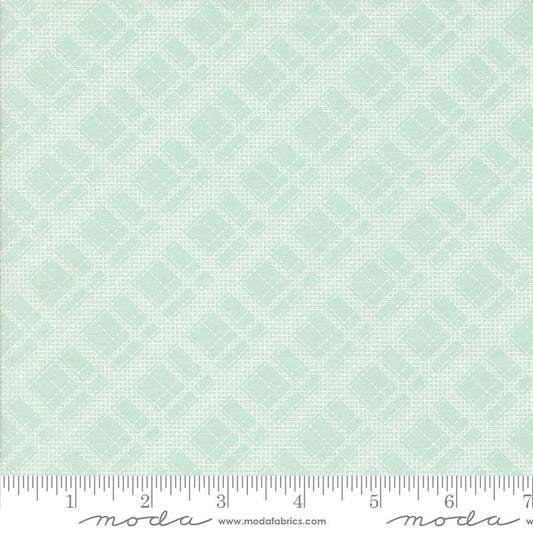 A close-up of a fabric pattern swatch in pale blue with a repeating small geometric diamond motif, plus a measuring ruler along the bottom edge and Moda branding.