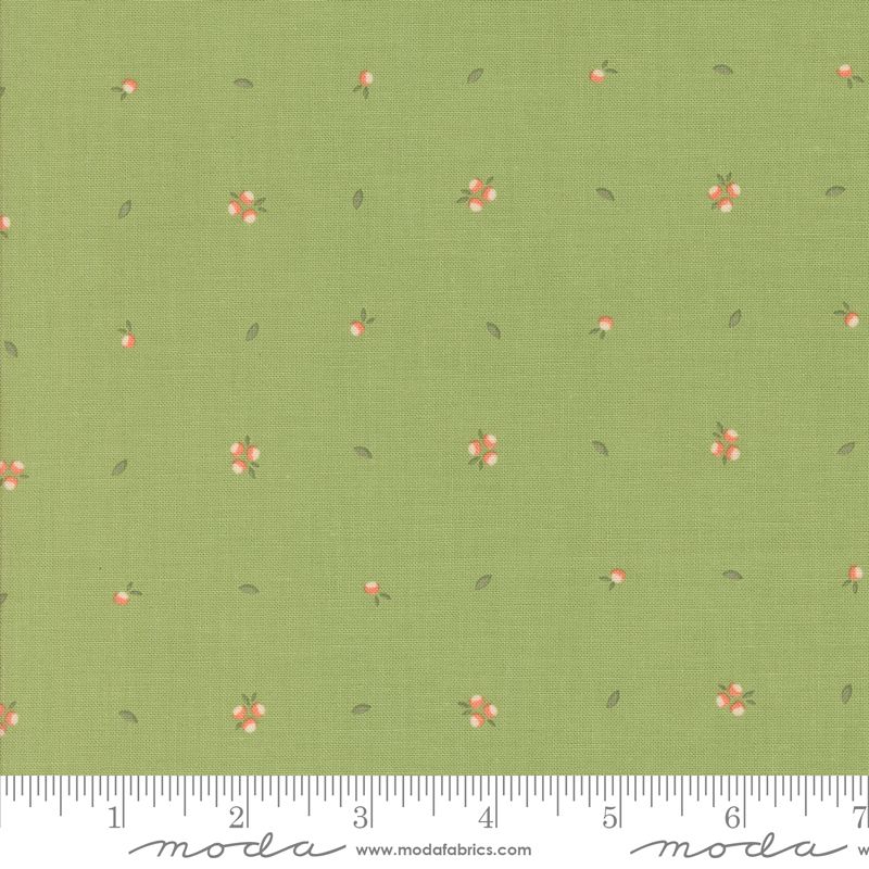 Green fabric with a repeating pattern of small pink flowers, white centers, and tiny green leaves, shown with a measuring ruler along the bottom edge. The brand name 'moda fabrics' is printed on the ruler.