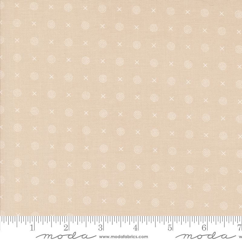 Beige fabric with a repeating white pattern of small crosses, dots, and short lines, shown with a ruler along the bottom edge and Moda Fabrics branding.