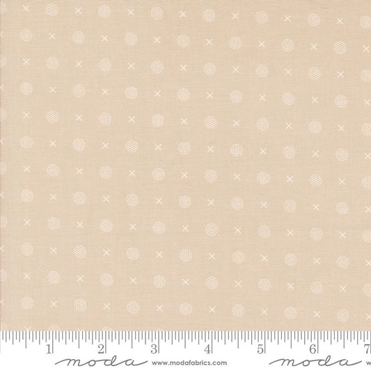 Beige fabric with a repeating white pattern of small crosses, dots, and short lines, shown with a ruler along the bottom edge and Moda Fabrics branding.