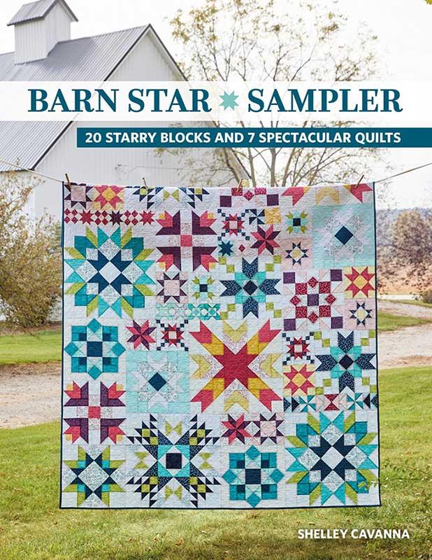 Quilt with star patterns displayed outdoors, with a barn in the background