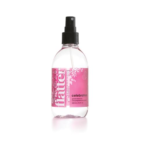 Clear spray bottle of Flatter Celebration scent fabric smoothing spray with pink label on a white background