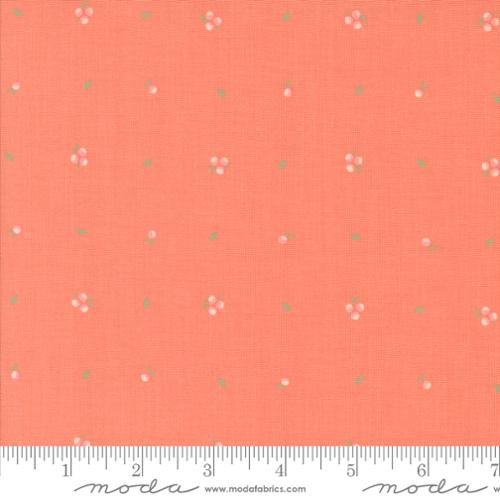 Coral pink fabric with a small white and green floral pattern, shown with a ruler at the bottom for scale. The brand name 'moda' is visible on the ruler watermark.