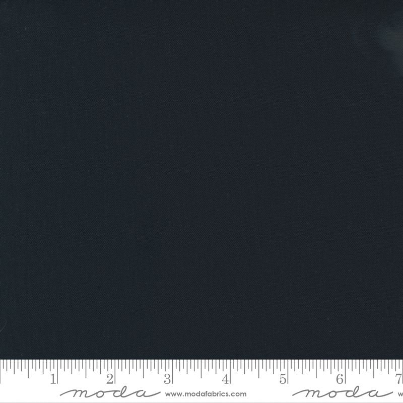 A close-up of a solid dark black fabric texture, with a white ruler at the bottom edge showing measurement markings and Modla branding.
