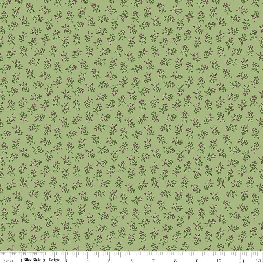 A repeating floral pattern on a light sage green background, featuring small purple and green blossoms. A white ruler at the bottom edge shows the brand 'Riley Blake Designs' and includes inch markings.