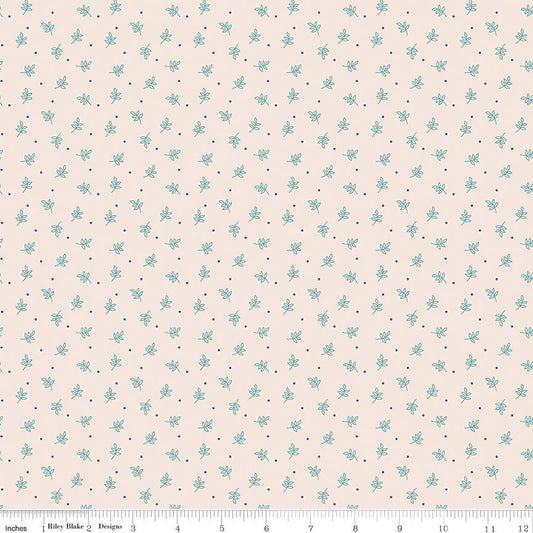 A repeating fabric pattern featuring small light blue floral motifs and tiny dark blue dots on a warm cream background, with a ruler along the bottom edge showing measurements.
