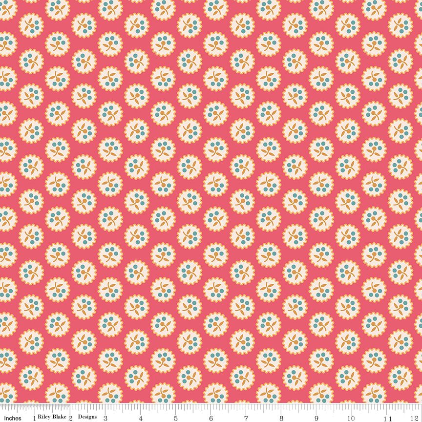 A repeating fabric pattern featuring retro-style circular floral medallions in cream, light blue, and orange on a coral pink background, with a ruler at the bottom indicating scale.