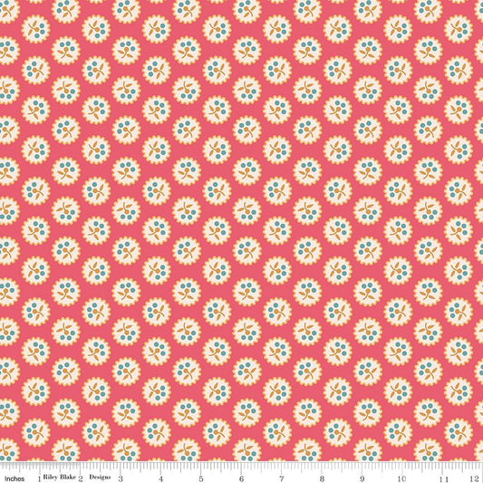 A repeating fabric pattern featuring retro-style circular floral medallions in cream, light blue, and orange on a coral pink background, with a ruler at the bottom indicating scale.