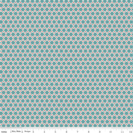 A repeating geometric pattern of small red and white circular motifs on a teal background, with a ruler along the bottom edge showing measurements. The text 'Riley Blake Designs' is visible on the ruler.