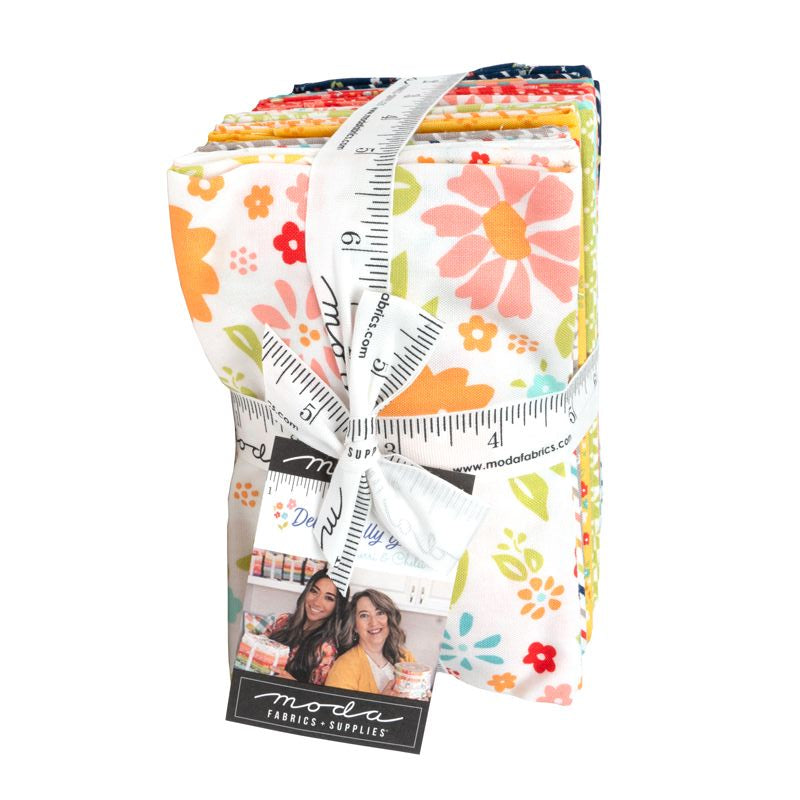 A fat eighth buncle of floral-patterned fabric wrapped with a white measuring tape and a black brand tag, photographed on a plain white background.