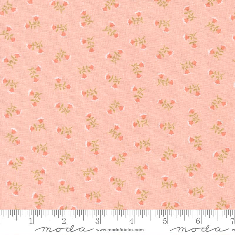 A close-up of a fabric pattern featuring small coral-pink flowers and olive-green stems on a soft peach-pink background, with a measuring ruler along the bottom edge showing the scale.
